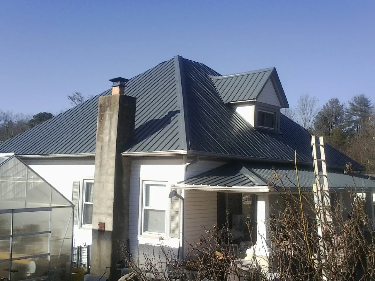 Dark blue standing seam metal roof on a white farmhouse with dormer — Slate & Tile Roof Repair by Roofing Brothers in Moss Landing