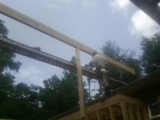 Carpenter setting a ridge beam over a new addition frame — Ice Dam Removal by Roofing Brothers in Moss Landing