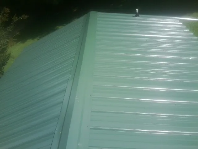 New green metal panels meeting at the ridge of a roof — Flat Roof Repair work by our crew in Moss Landing