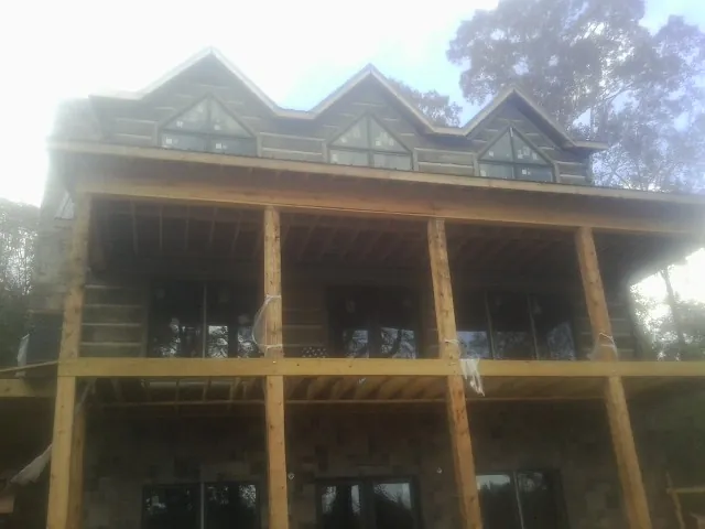 Dormers and porch framing on a large log home under construction — Roof Coating work by our crew in Moss Landing