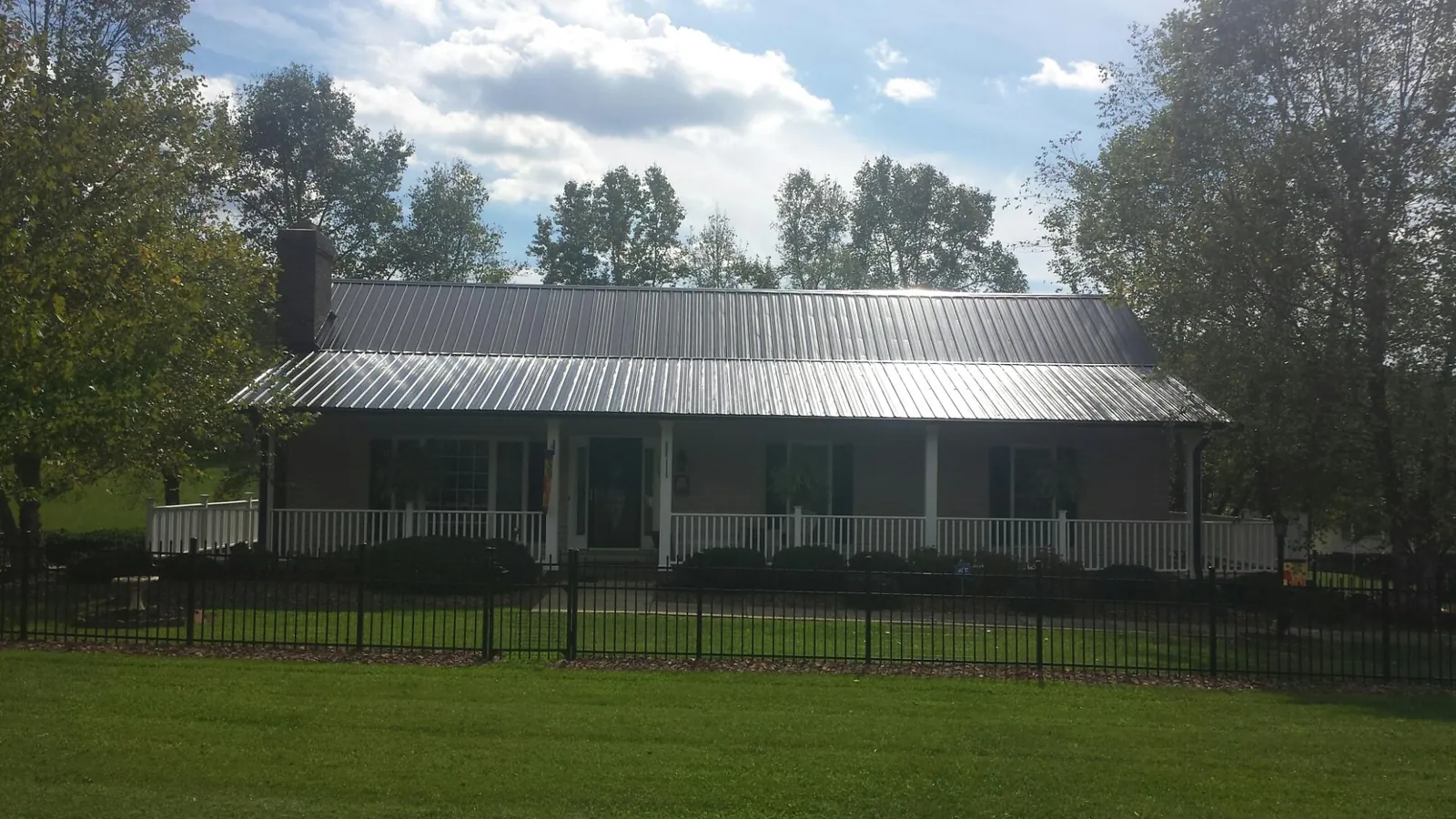 Gray metal roof on a brick ranch with a full width front porch — Gutter Guard Installation work by our crew in Moss Landing
