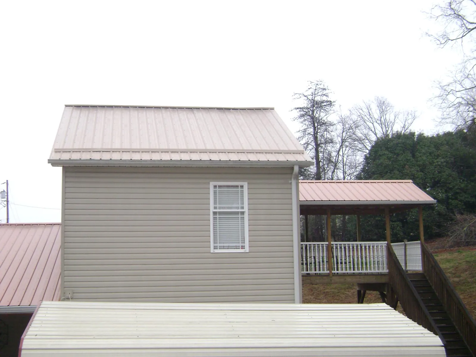 Tan metal roofs on a two story addition and attached porch, from a Roof Replacement job in Moss Landing