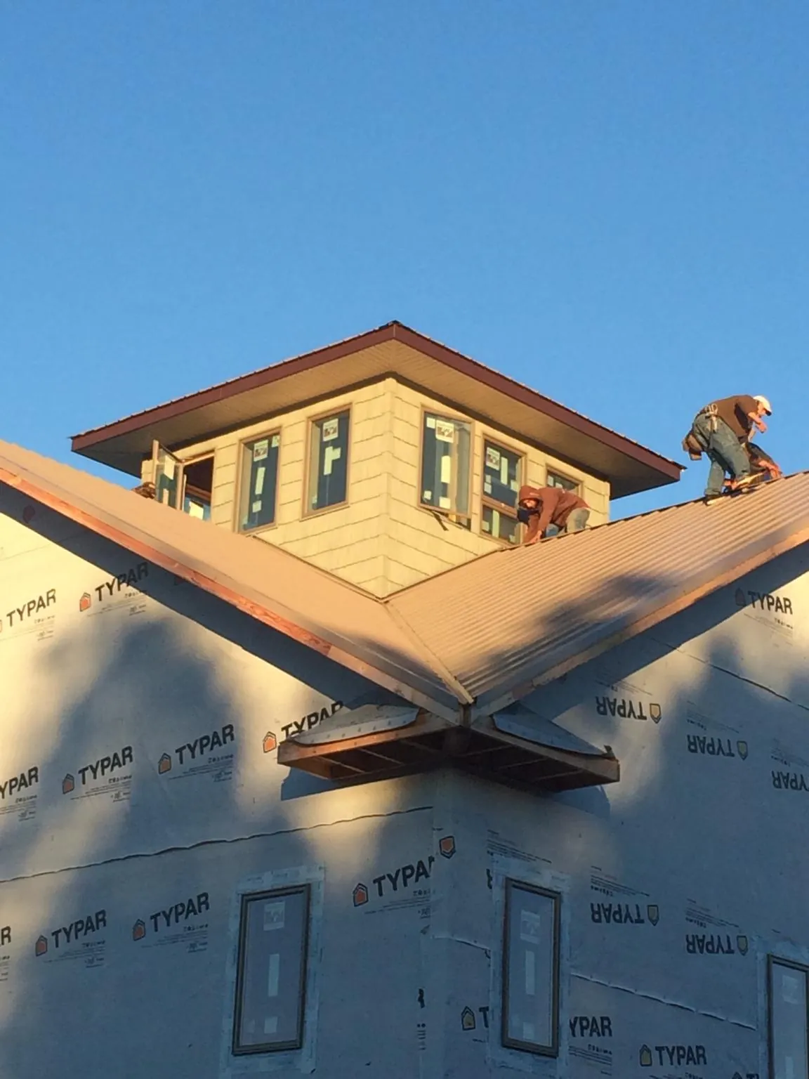 Roofers working around a rooftop cupola on a new metal roof at sunset — Roof Waterproofing in Moss Landing by Roofing Brothers